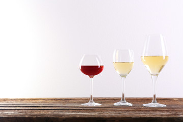 Wine and grape on wooden table against light background