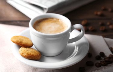 Cup of coffee, cookie and newspaper on wooden table background