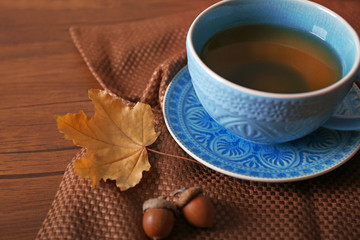 Cup of tea with autumn decor on wooden table.