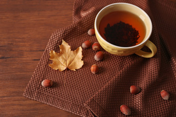 Cup of tea with autumn decor on wooden table.