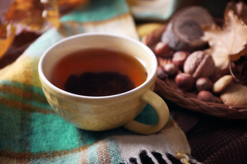 Cup of tea with autumn decor on wooden table.