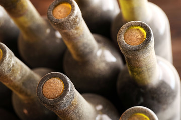 Stacks of dusty wine bottles on wooden background, upside view. Close up