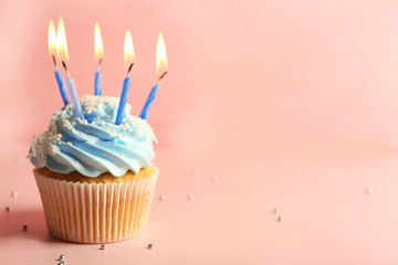 Tasty cupcake decorated with candle on pink background