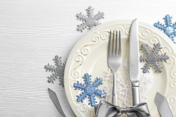 Christmas serving cutlery on plate over light wooden table, close up
