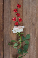 Rose on a wood background with chocolate in a shape of heart