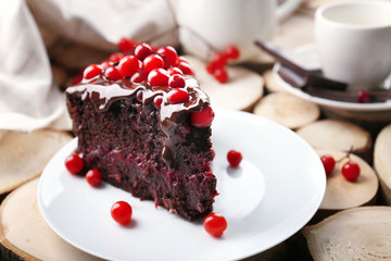 Piece of chocolate cake with cranberries on wooden background, closeup