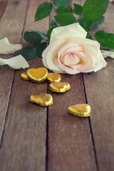 Rose on a wood background with chocolate in a shape of heart
