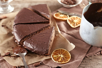 Sliced chocolate frosting cake on wooden table