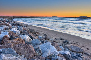 Large rocks and jetty form a perimeter around the surf. 