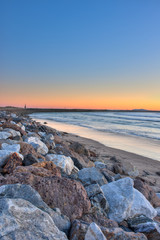 Portrait view of large rocks and jetty creating a perimeter around the surf. 