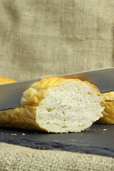 French stick bread cutting / Cutting a French stick loaf on a slate chopping board.