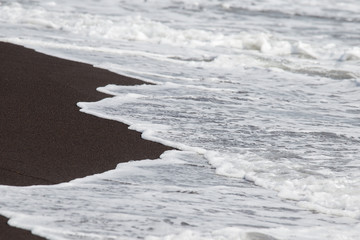 Black volcanic sand and waves on the beach in Legazpi, Philippines