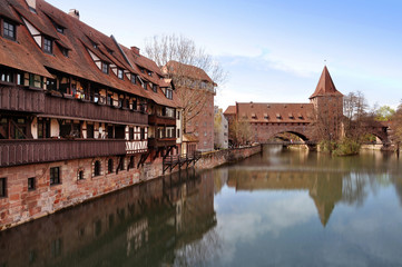 Fototapeta premium Old buildings and arch bridge reflected in water. Nuremberg, Bayern, Germany