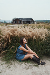 Naklejka na ściany i meble cute countryside lady sits n tall grass against ranch house