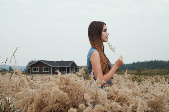 cute countryside lady standing in tall grass against ranch house