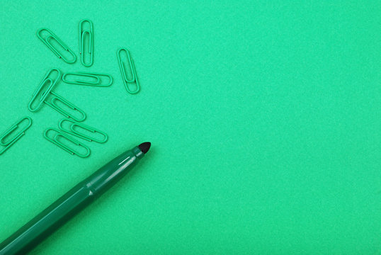 green marker and paperclips on a green cardboard