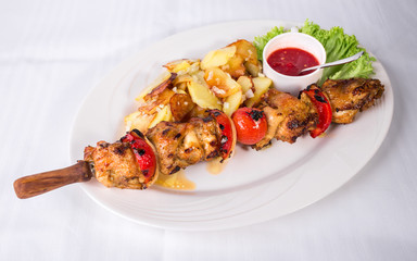 Grilled chicken shish kebab with red sauce.