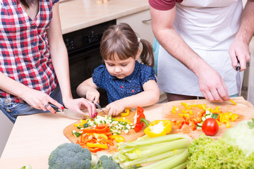 mother and father teaching girl how to cook