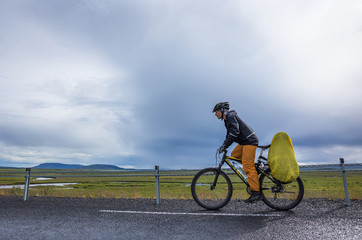 Biker rides on road at sunny summer day in Iceland - Powered by Adobe