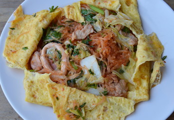 stir fried sukiyaki with seafood wrapped in egg on dish