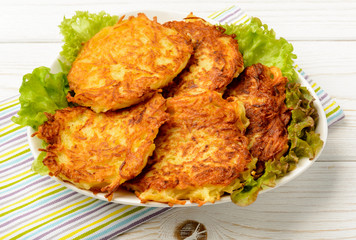 Potato pancakes on white wooden table.