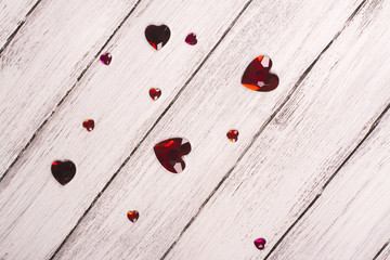 St Valentine day background. Small glass hearts over white wooden table. Copy space for text