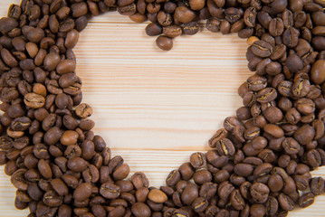 Heart shape made from coffee beans on wooden surface. coffee in the shape of a heart. Valentine's Day, concept of love.
