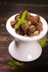 Chocolate truffle candies and assortment of nuts over grunge wooden table. Toned image. Selective focus