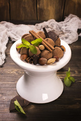 Chocolate truffle candies and assortment of nuts over grunge wooden table. Toned image. Selective focus