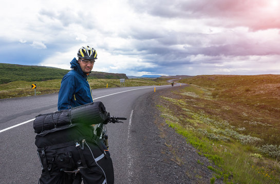 Biker rides on road at sunny summer day in Iceland. Travel and sport picture