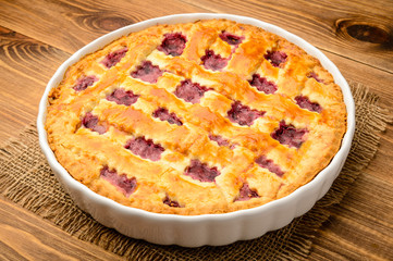 Cherry pie on brown wooden table.