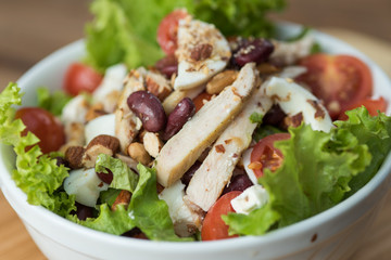 Fresh cesar salad served in a ceramic bowl on the wooden board