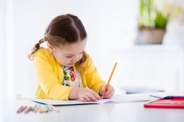 Little girl painting and writing