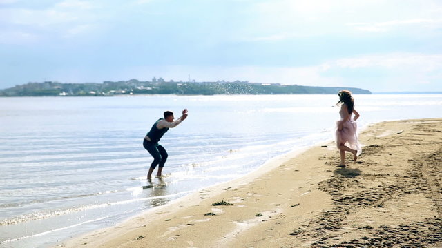 Man and woman, young people, happy married adult couple having fun and playing on the shore, beach. HD.