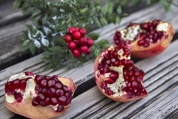 Juicy pomegranate fruit and red flower over wooden table
