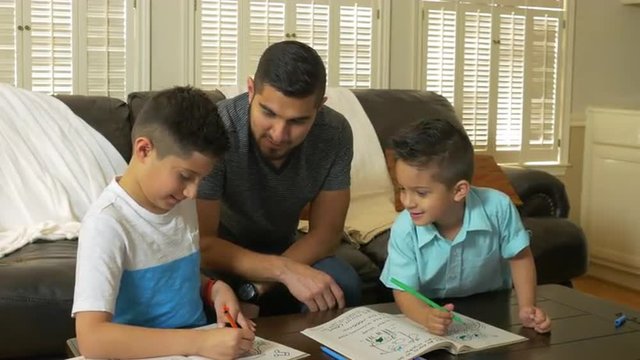 Father spending quality time with his sons as the draw and color in workbooks.