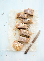 Homemade apple and almond strudel on baking paper over light blue wooden backdrop