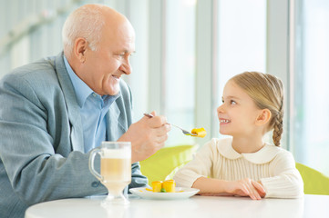 Obraz na płótnie Canvas Grandfather asking granddaughter to try a pie.