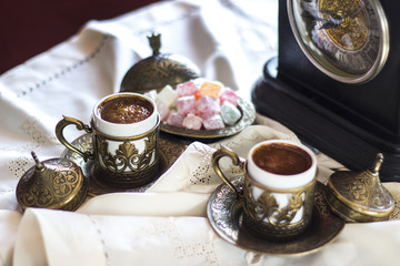 Turkish coffee with delight and traditional copper serving set, vintage clock
