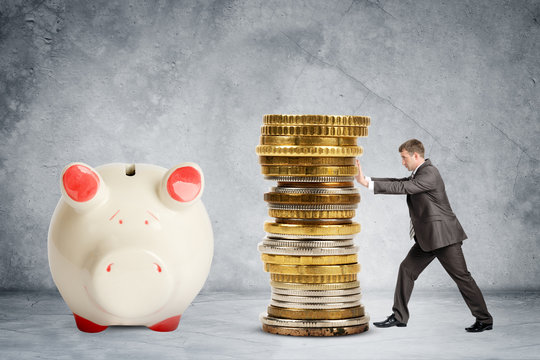 Businessman pushing pile of coins