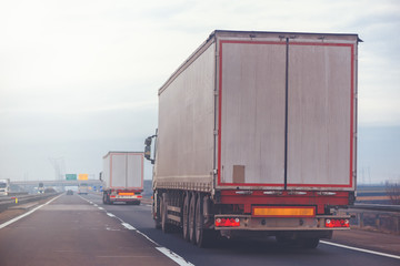 Commercial trailer truck in motion on freeway on cloudy afternoo