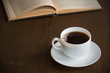 Cup of coffee with a book on a grunge wooden table