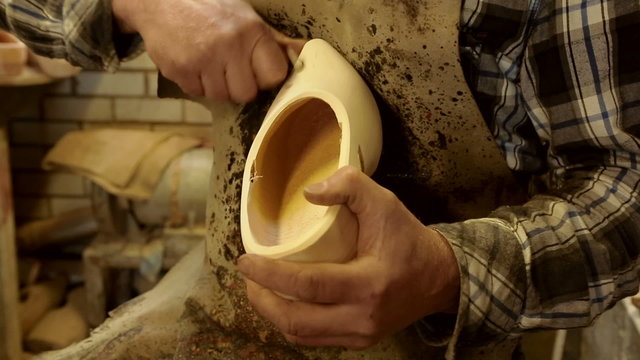 Clog maker is cutting decoration in clog with a gouge