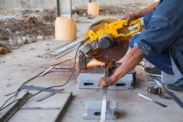 spark from worker cutting metal by hacksaw at construction site