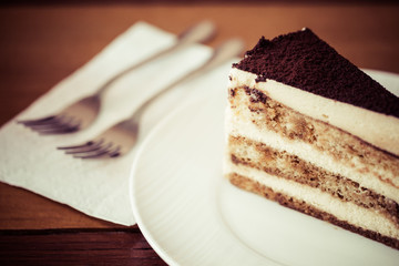 Tiramisu in the plate on the wooden background, process color