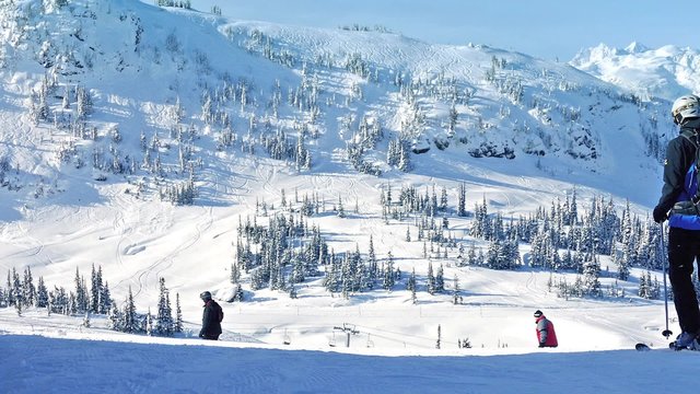 People Ski Past Near Huge Snowy Mountain