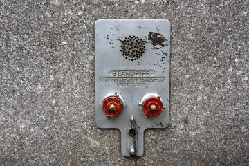 Standpipe connectors. Metal fire department standpipe connections with red covers on granite wall...