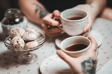 a guy and a girl with two cups of tea at a beautiful table with gingerbread