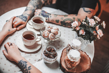 a guy and a girl with two cups of tea at a beautiful table with gingerbread