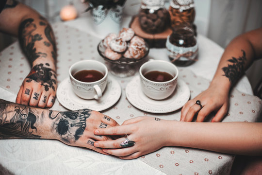 a guy and a girl with two cups of tea at a beautiful table with gingerbread
